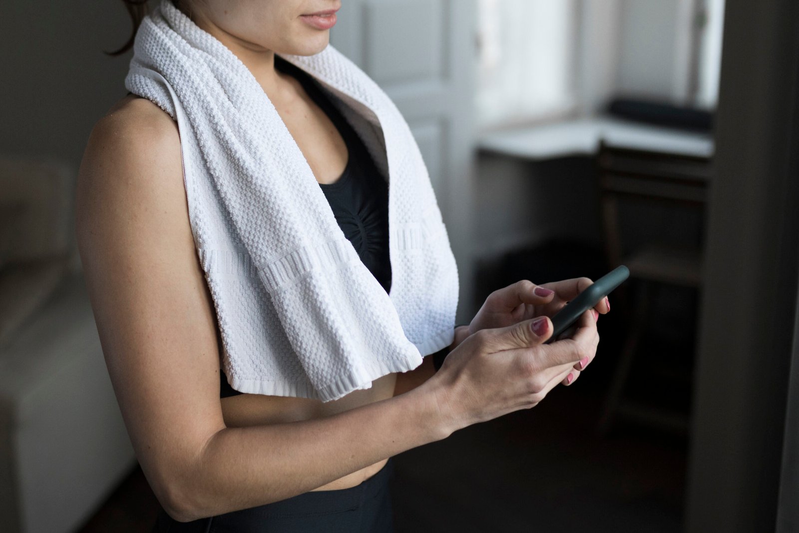 side-view-woman-with-towel-shoulders-using-smartwatch